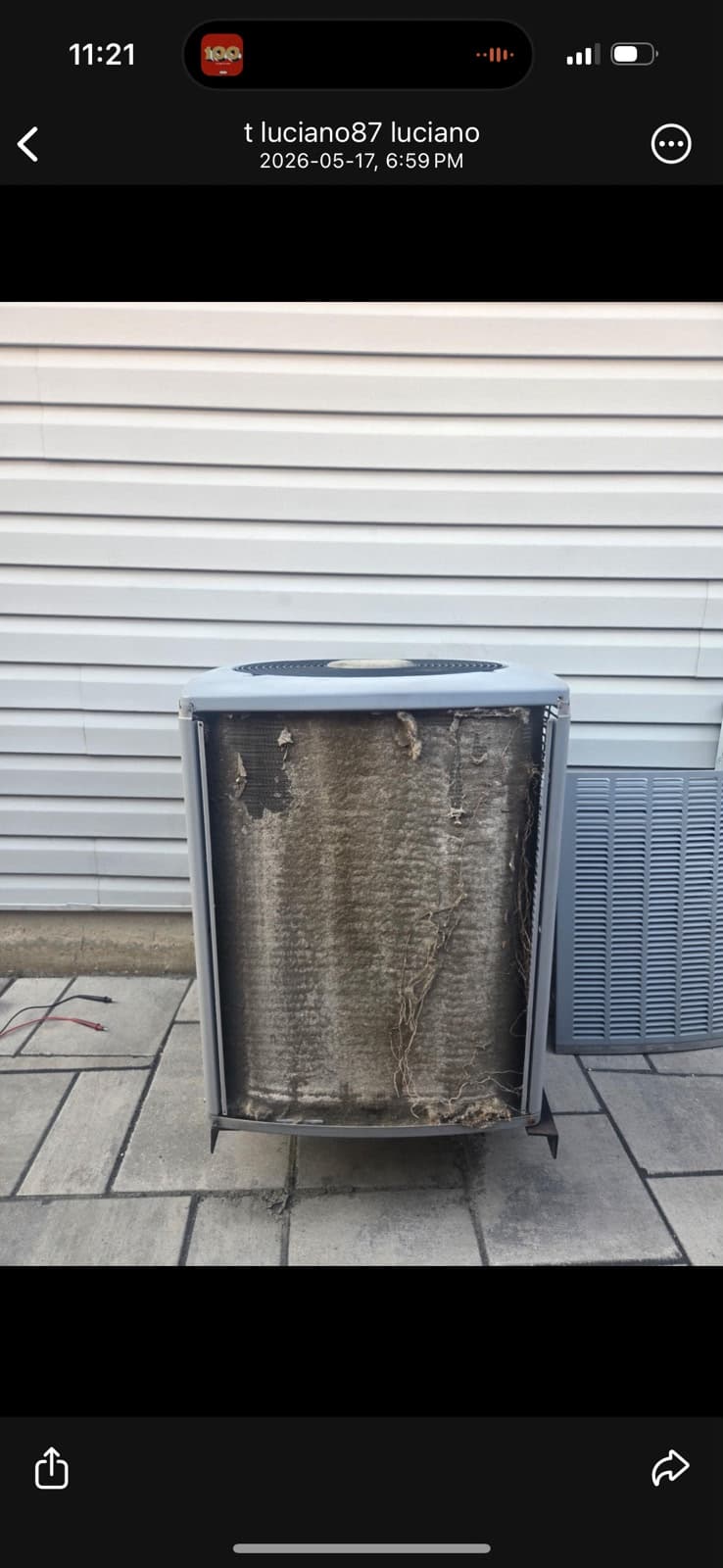 Severely clogged residential A/C condenser coil with cottonwood, grass clippings, and debris build-up — before cleaning